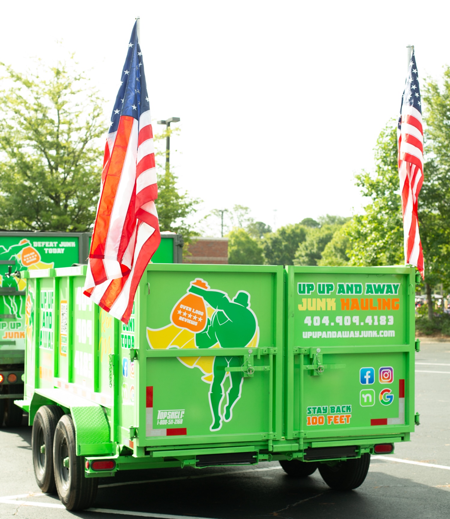 Green junk hauling trailer with superhero logo and American flags.