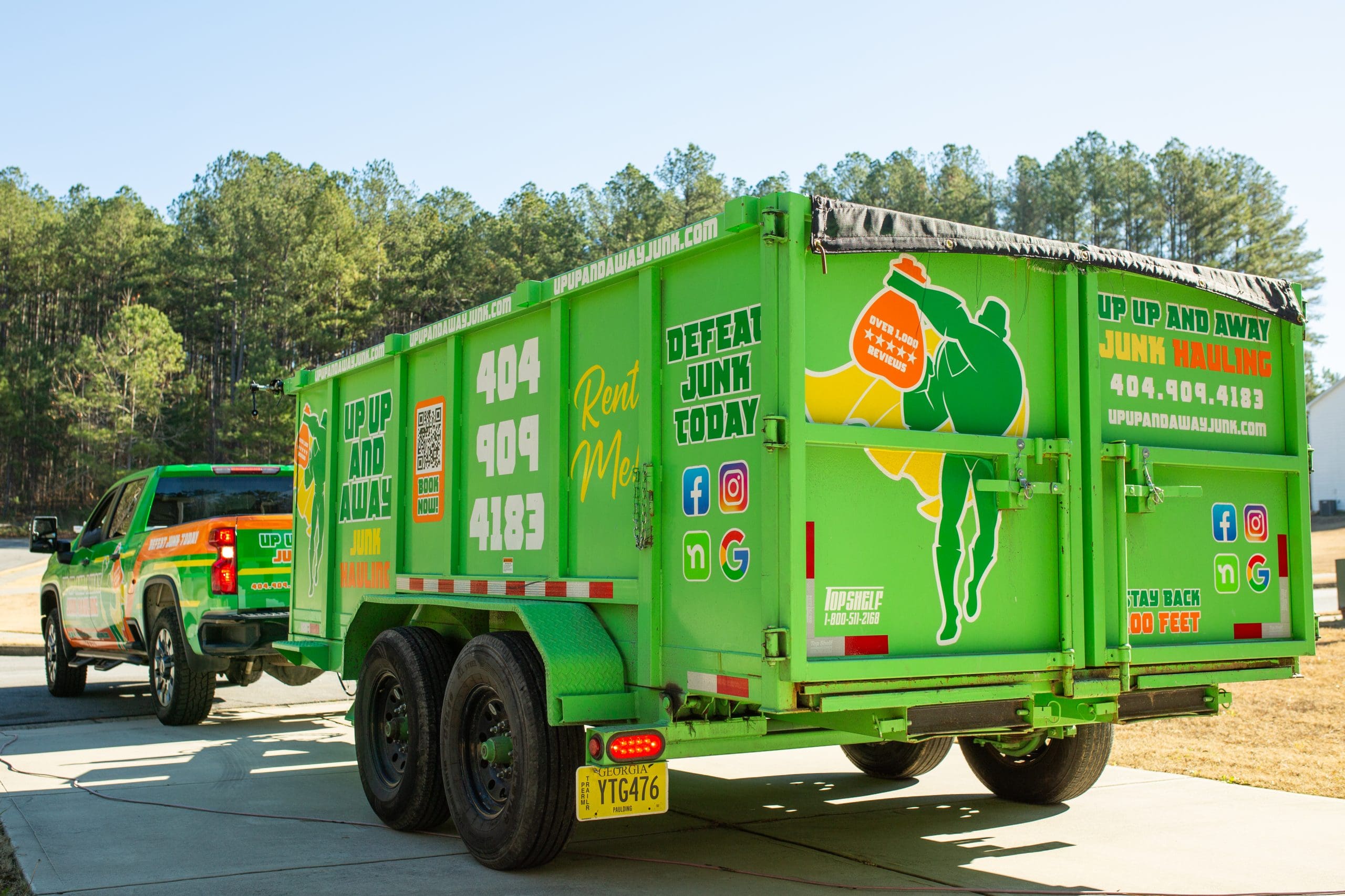Green junk hauling trailer with superhero logo and contact info.